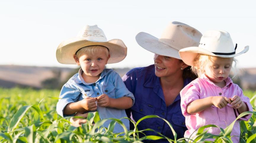 Woman and children wearing hats in field.